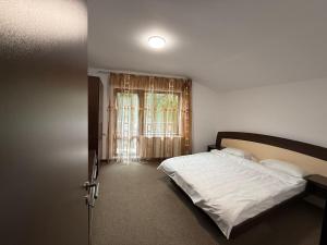 ein Schlafzimmer mit einem weißen Bett und einem Fenster in der Unterkunft AMK House - Busteni in Buşteni