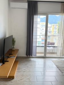 a living room with a television and a large window at Bejart Apartment 7 in Tirana
