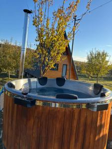 a wooden tub with a house in the background at Cabana Teo&Matei in Mihăeşti