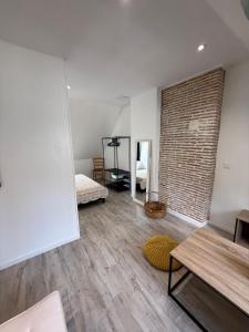 una sala de estar con una pared de ladrillo y una habitación con dos camas en Sous les Toits de Boussac, en Boussac