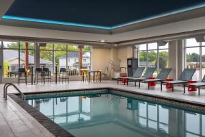 a pool with chairs and tables in a hotel room at Home2 Suites By Hilton Woodstock On in Woodstock