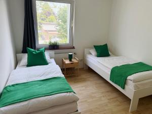 2 Betten in einem Zimmer mit grünen Kissen in der Unterkunft Siegburg EG rechts in Siegburg