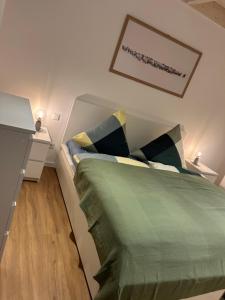 ein Schlafzimmer mit einem Bett mit einer grünen Bettdecke in der Unterkunft Apartment Deich - Moment in Krummendeich