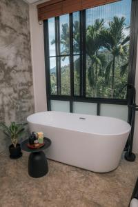 Una bañera blanca en un baño con ventana. en KAI BAE BALCONY Hills Bungalows Koh Chang, en Khlaung Phai Bae 68 fotos más