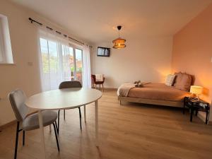 ein Schlafzimmer mit Bett und Tisch und ein Esszimmer in der Unterkunft Le clos des roses in Ingersheim