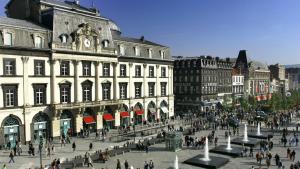 a group of people walking around a city with buildings at Hôtel Saint André Gare SNCF in Clermont-Ferrand