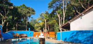 a swimming pool with a blue fence and trees at Pousada Cantinho do Sagui Inn in Búzios