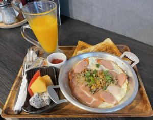 a tray with a bowl of food and a glass of orange juice at ณิชาวิลล่า ริเวอร์ฟร้อนท์บ้านท่าตอน in Mae Ai Chiang Mai