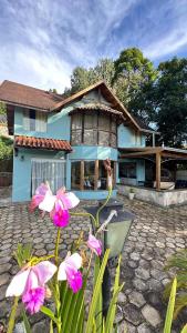 a blue house with pink flowers in front of it at Casa na Montanha em Monte Verde in Monte Verde