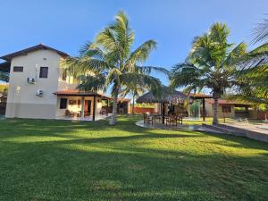 a house with palm trees in front of a yard at Rota do Mar in Luis Correia