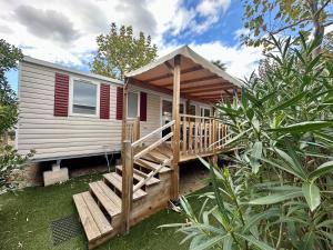 a tiny house with a porch and a deck at Mobil-home camping 4 étoiles à Valras-Plage Clim Piscine Proche Mer 6 à 8 pers in Valras-Plage