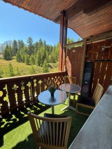 un patio con 2 mesas y sillas en un porche en Appart 60 M2 pied pistes terrasse Vars les Claux, en Vars