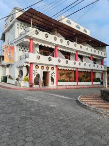 a large white building with red columns on a street at Royal Galápagos Inn in Puerto Baquerizo Moreno