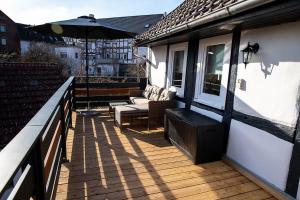 an outdoor deck with an umbrella and a couch and chair at Ferienhaus Lotte in Vöhl