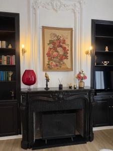 a fireplace in a living room with a painting on the wall at La Rose des Vins in Pouzolles