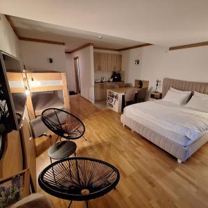 a bedroom with a bed and two chairs and a kitchen at Apartman 452 sa pogledom na stazu Hotel Vučko private host in Jahorina