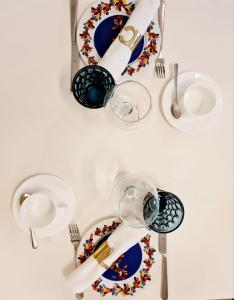 a table with plates and glasses and utensils at La Casa del Moro Pachino in Pachino