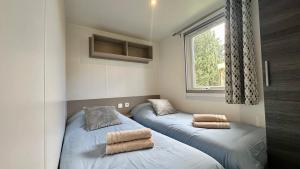 two beds in a small room with a window at Mobil-home camping 4 étoiles à Valras-Plage Clim Piscine Proche Mer 6 à 8 pers in Valras-Plage +11 photos