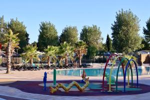 a playground in a park with a swimming pool at Mobil-home camping 4 étoiles à Valras-Plage Clim Piscine Proche Mer 6 à 8 pers in Valras-Plage