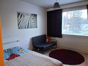 Un dormitorio con una cama, una silla y una ventana en Cozy and family friendly apartment, en Rovaniemi