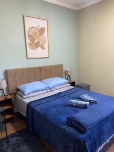 um quarto com uma cama com lençóis azuis e uma imagem na parede em Duas Suites aconchegantes em frente a Montanha em Poços de Caldas
