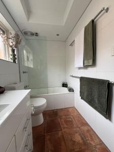 a white bathroom with a toilet and a bath tub at Fulton Flow Resort Apartment in Melbourne