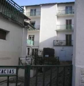 - un bâtiment blanc avec un balcon et un panneau en face dans l'établissement Appartement Résidence les Acacias, à Ax-les-Thermes