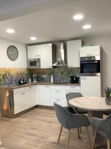 a kitchen with white cabinets and a table and a clock at Urlaub im Münsterland in Osterbauerschaft