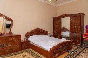 ein Schlafzimmer mit einem Bett, einer Kommode und einem Spiegel in der Unterkunft Orzu Guest House in Samarkand