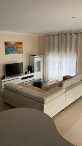 a living room with a large couch and a television at Maison vacances - cure thermale in Eugénie-les-Bains +4 photos