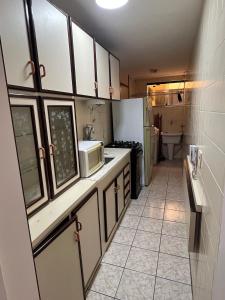 een kleine keuken met een spoelbak en een magnetron bij Apartamento 3 suítes perto da Praia do forte e Passagem in Cabo Frio