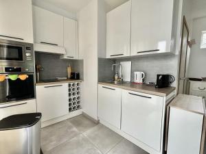 a white kitchen with white cabinets and appliances at L'Appartement du Port in Étaples