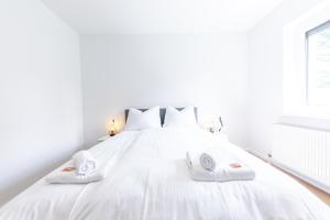 a white bed with white pillows and towels on it at Touch Upon Metropolis by JR City Apartments in Gerasdorf bei Wien