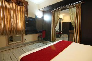 Dormitorio con cama, escritorio y TV en Le Grand Hotel, en Haridwar