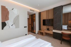 a bedroom with a bed and a flat screen tv at Tradicija Hotel in Železnička Stanica Incel