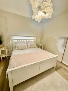 a white bed in a bedroom with a chandelier at Ferienwohnung am Olantis in Oldenburg