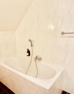 a white bath tub with a shower in a bathroom at Secondo Piano Hasselt in Hasselt