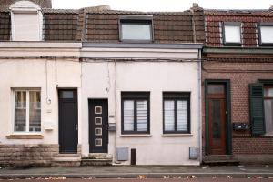 Weißes Haus mit schwarzen Türen und Fenstern in der Unterkunft Maison 2 ch, 3 lits, près de Lille & transports in Lezennes