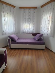 a purple couch in a room with two windows at Villa Big Mama in Živinice