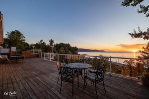 a table and chairs on a deck with a view of the water at La Maison Jaune in La Malbaie +38 photos