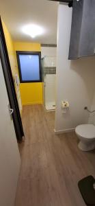 a bathroom with a toilet and a yellow wall at Colorama in Nozay
