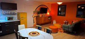 a kitchen with a table and a dining room with orange walls at Colorama in Nozay +13 photos
