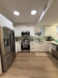 Una cocina con gabinetes blancos y un refrigerador de acero inoxidable. en Cozy 2BR retreat in Rosewood, en Saskatoon