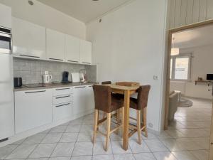 a kitchen with white cabinets and a wooden table at Le Nid du Port in Étaples +8 photos