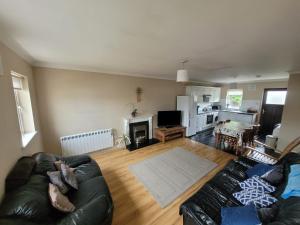 a living room with a black leather couch and a kitchen at Holiday cottage Wexford, Riverchapel Gorey in Riverchapel