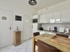 a kitchen with a wooden table and a kitchen with white cabinets at Le Nid du Port in Étaples