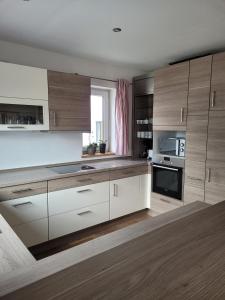 a large kitchen with wooden cabinets and a sink at Ferienwohnung Harpfing in Schnaitsee