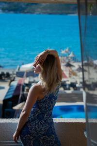 Eine Frau, die auf einem Geländer sitzt und den Ozean ansieht. in der Unterkunft Oscar Seaside & Spa Hotel by Club Aquarium in Guvercinlik