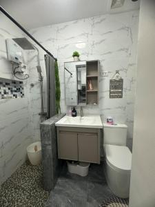 a bathroom with a sink and a toilet and a tub at Amado Apartelle 1 Tagaytay in Kaybagal