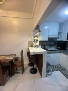 a kitchen with white cabinets and a table and chairs at Amado Apartelle 1 Tagaytay in Kaybagal